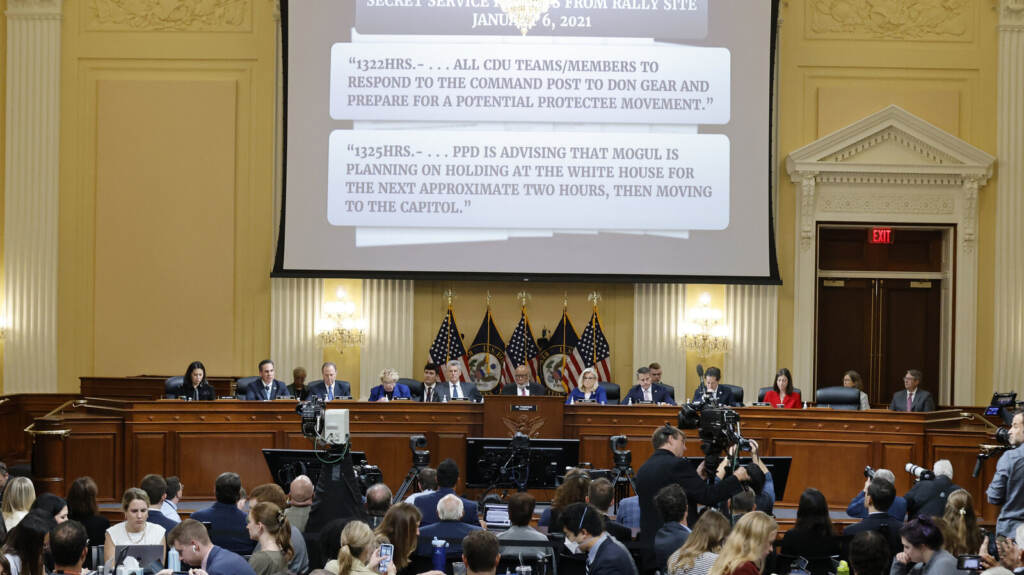 January 6th Committee Holds First Hearing Since July The Jan. 6 commission shows something on a projector screen.