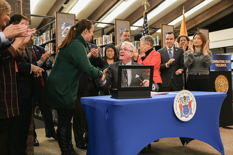 A person shakes Gov. Murphy's hand as he is seated at a table surrounded by people.