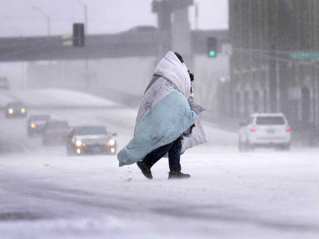 Winter Weather Missouri A person wrapped in a blanket crosses a snow-covered street
