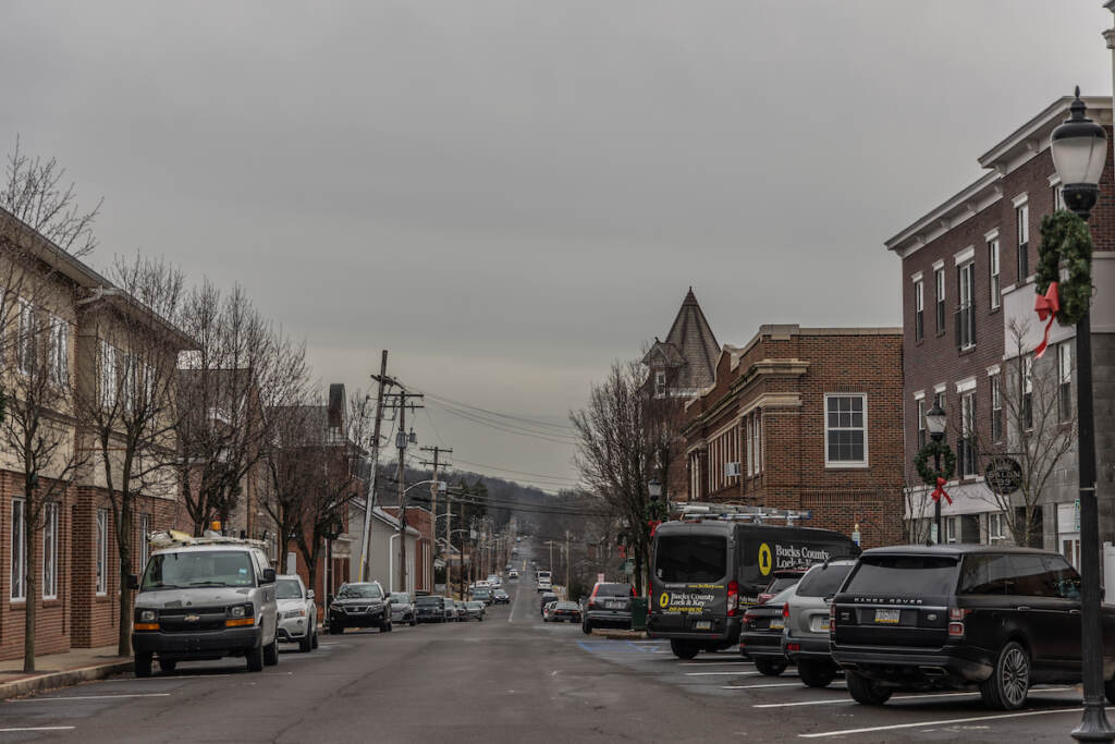 A road stretches into the distances, buildings on either side, on an overcast day.