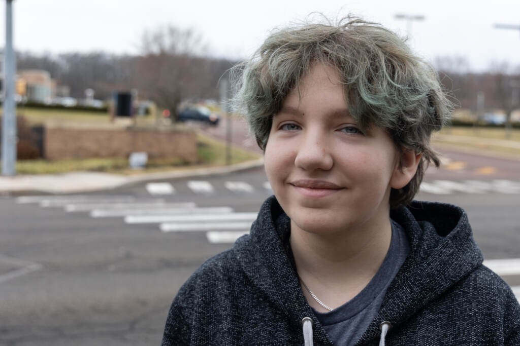 Silas Nathan poses for a photo. A road is visible in the background.