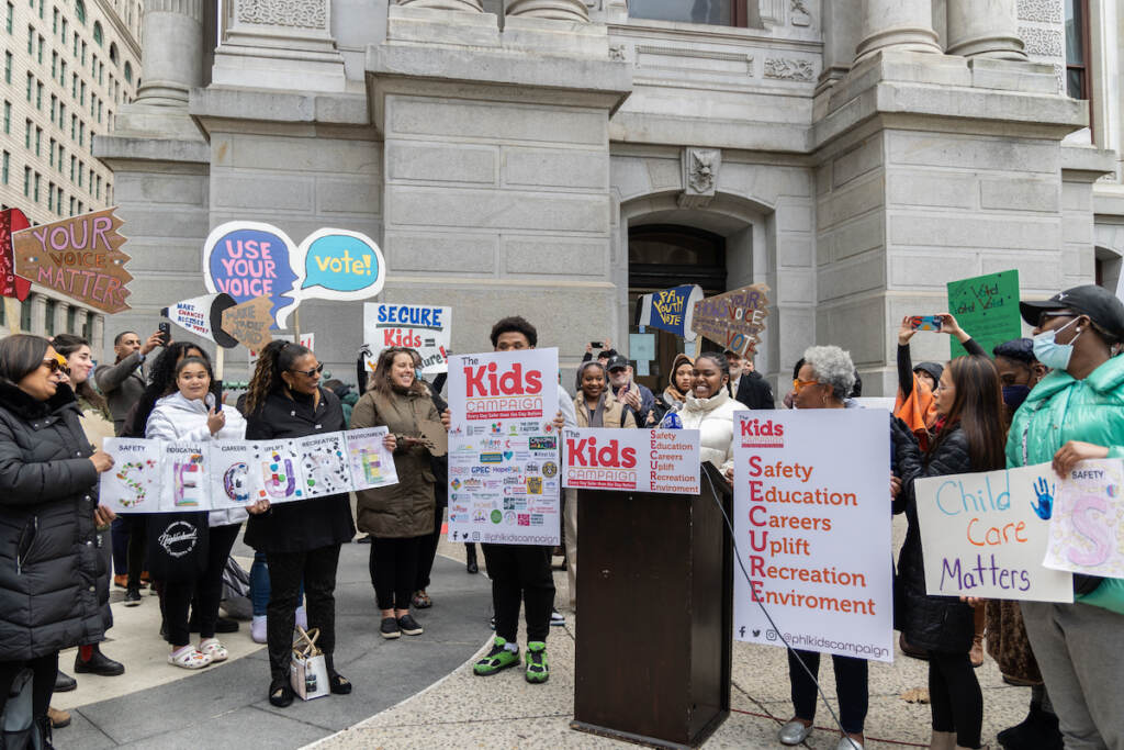01 20 2023 k paynter student kids campaign launch A group of people gather outside of City hall holding signs that reads