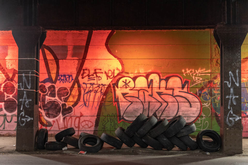 01 31 2023 k paynter illegal dumping Tires are seen left in an underpass. Graffiti on the wall behind it is visible.