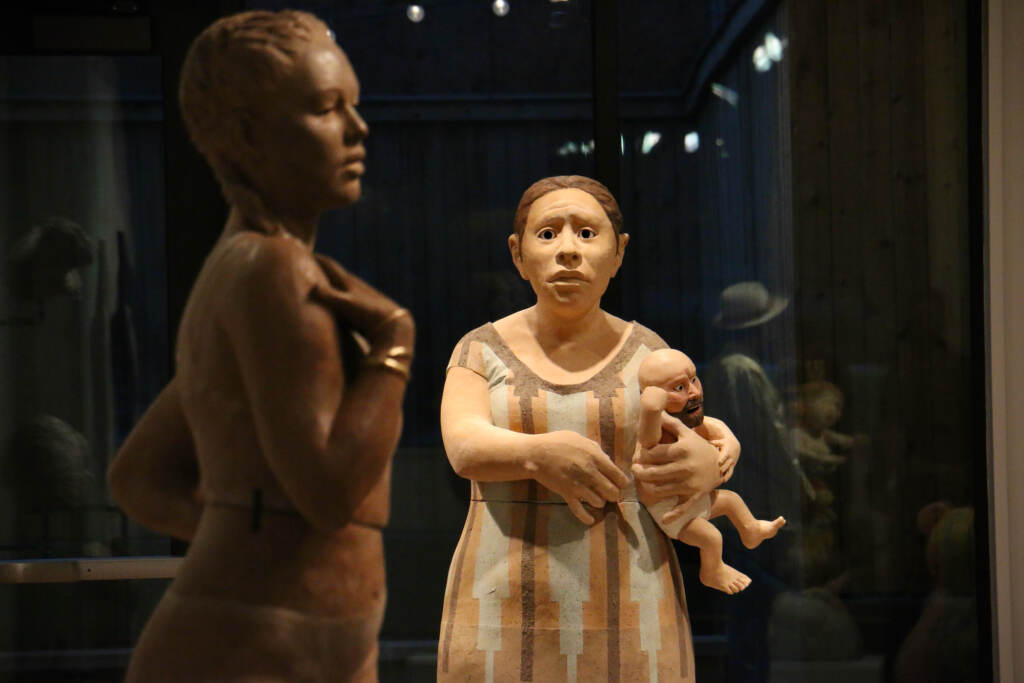 2023 01 12-e lee-philadelphia clay studio-figuring space put down the man baby A figure holding a man baby gazes towards another sculpted figure.