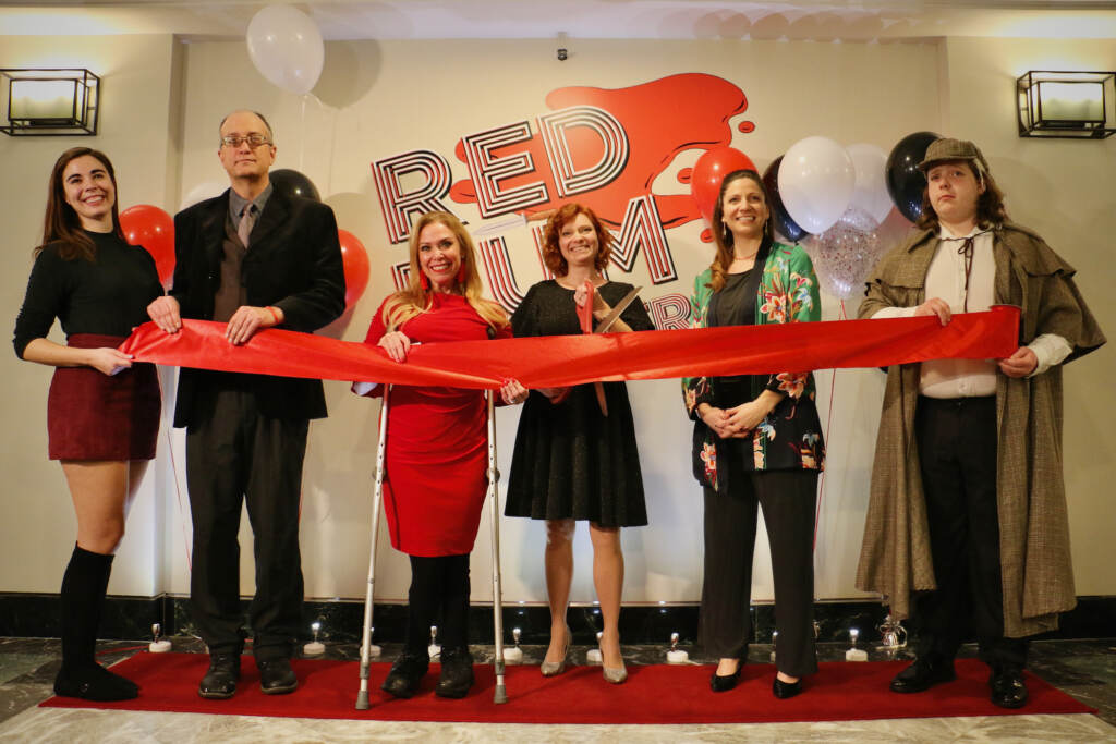 2023 01 12-e lee-traci connaughton-philadelphia curtis building-red rum theater ribbon cutting A row of people hold red tape and pose for a photo.