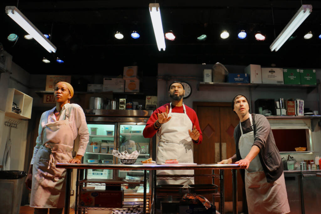 2023 01 26-e lee-kishia nixon walter deshields j hernandez-philadelphia arden theatre company-clydes A group of people onstage stand in a kitchen.