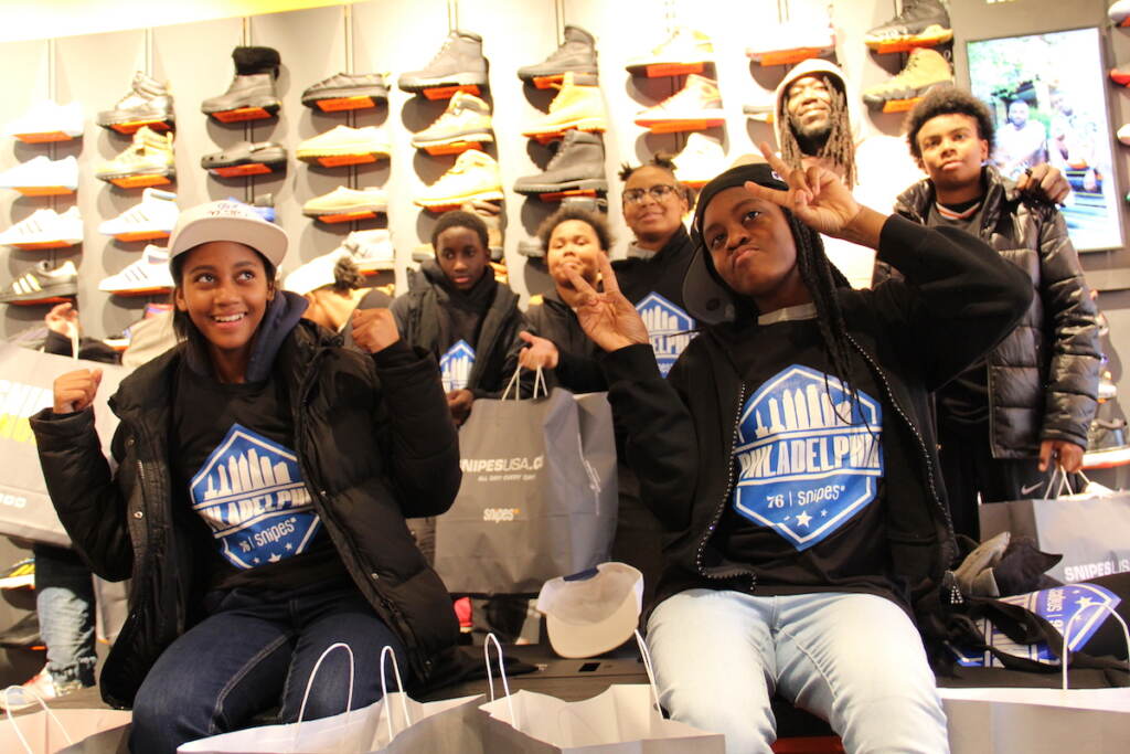 76ers-rec-center-1JPG Kids pose for a photo, holding up the peace sign. Sneakers are visible in the background.