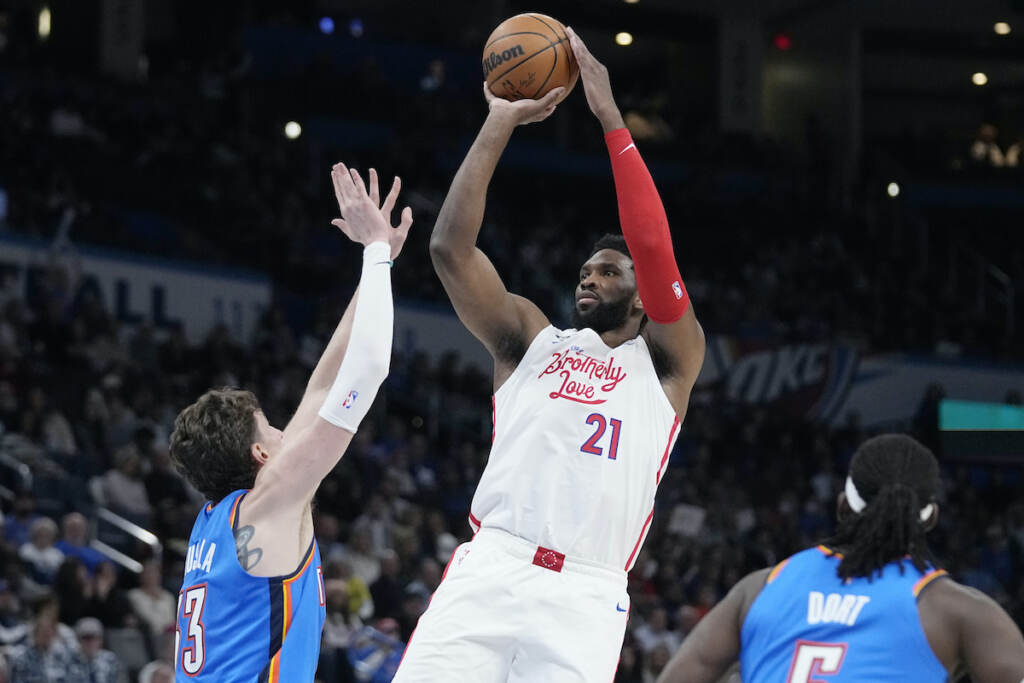 Joel Embiid,Mike Muscala,Luguentz Dort Philadelphia 76ers center Joel Embiid (21) shoots between Oklahoma City Thunder center Mike Muscala, left, and guard Luguentz Dort, right, in the first half of an NBA basketball game Saturday, Dec. 31, 2022, in Oklahoma City. (AP Photo/Sue Ogrocki)