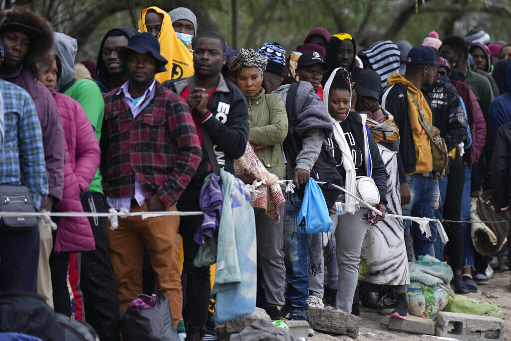 Biden Border A group of people stand in a line.