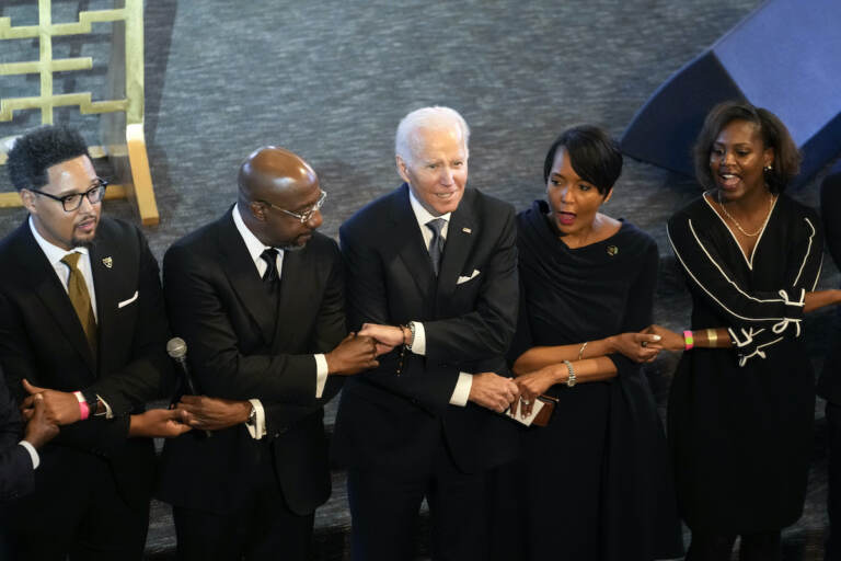 President Joe Biden, center, holds hands with Sen. Raphael Warnock, D-Ga., a senior pastor at Ebenezer Baptist Church, second from left, and Keisha Lance Bottoms, senior adviser to Biden for public engagement and former Atlanta Mayor, second from right, after Biden spoke at Ebenezer Baptist Church in Atlanta, Sunday, Jan. 15, 2023, during a service honoring Martin Luther King Jr