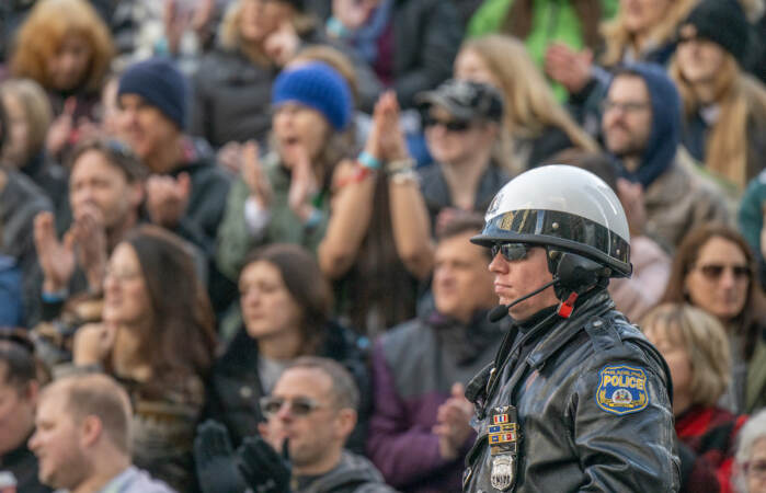 As crowds cheer in the background, a stoic highway patroman stands guard on South Penn Square. (Jonathan Wilson for WHY)