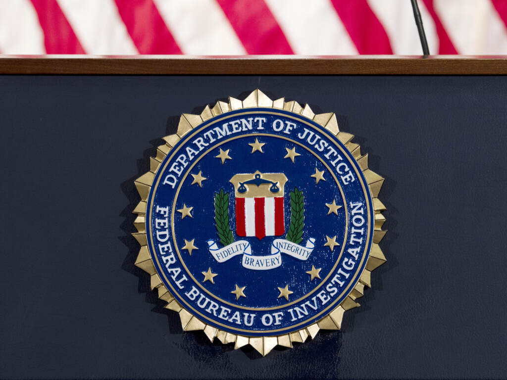 The FBI seal is displayed on a podium. A former FBI agent is facing several charges tied to his work with a Russian oligarch. The FBI seal is displayed on a podium.
