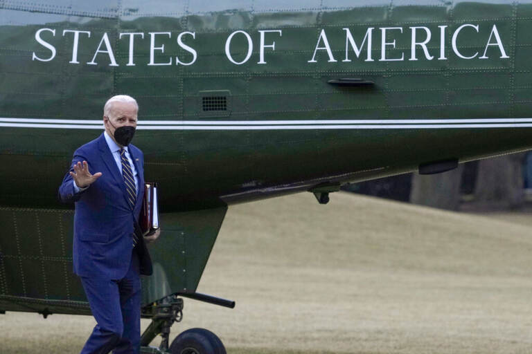 President Biden waves while walking towards a plane.