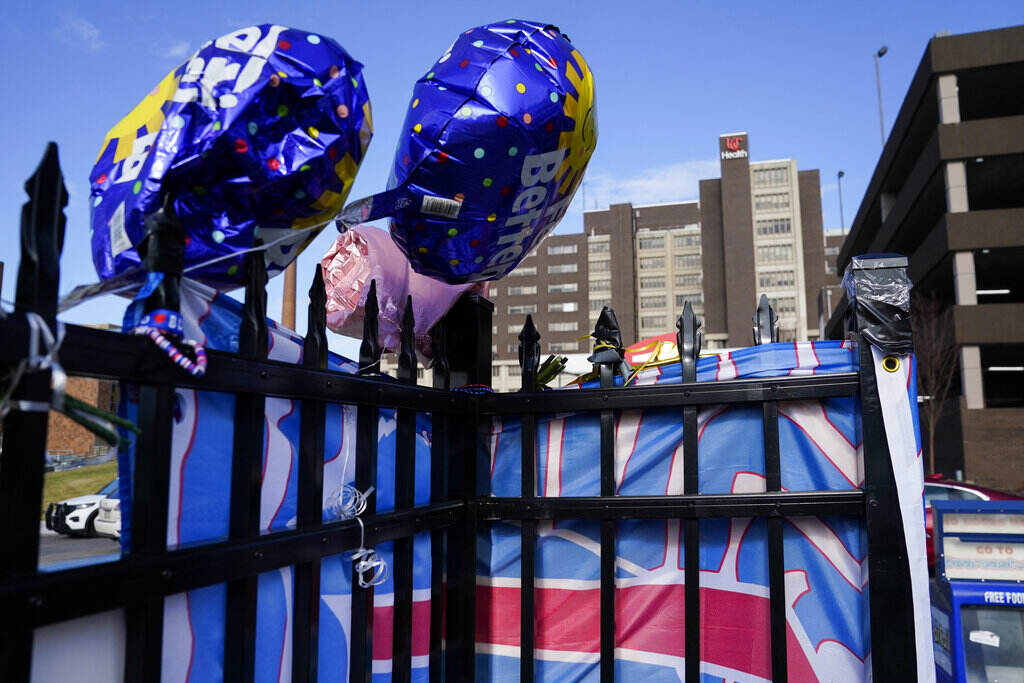 Ballons are displayed on a fence outside of a hospital building.