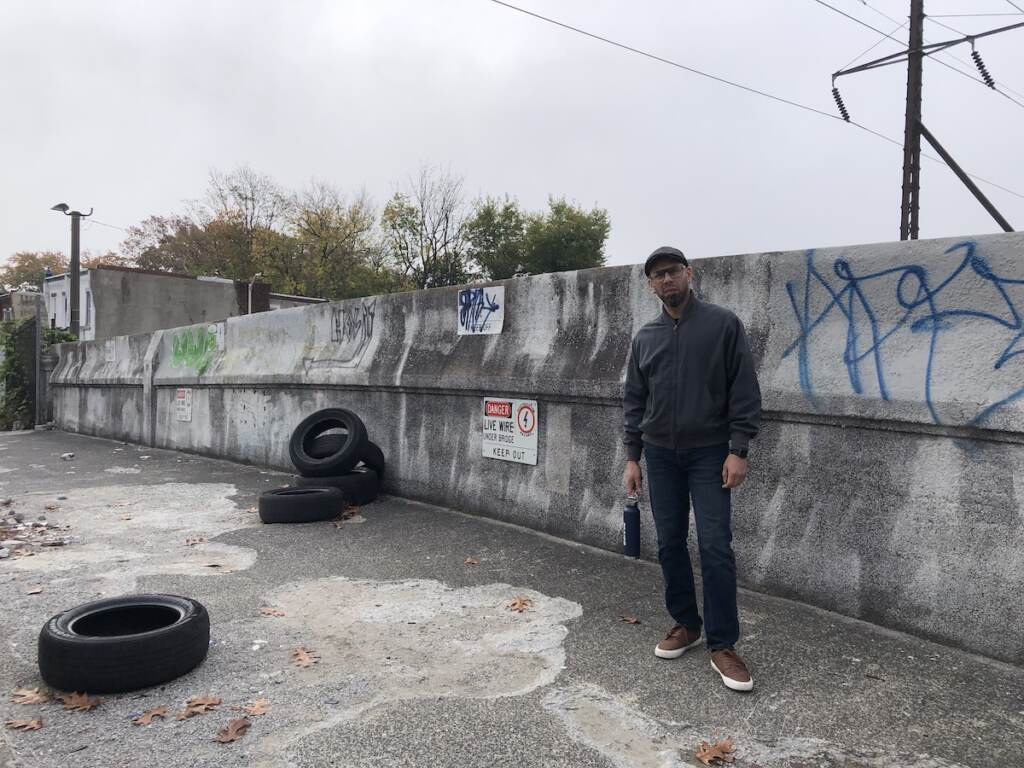 A man stands next to tires dumped on a bridge.