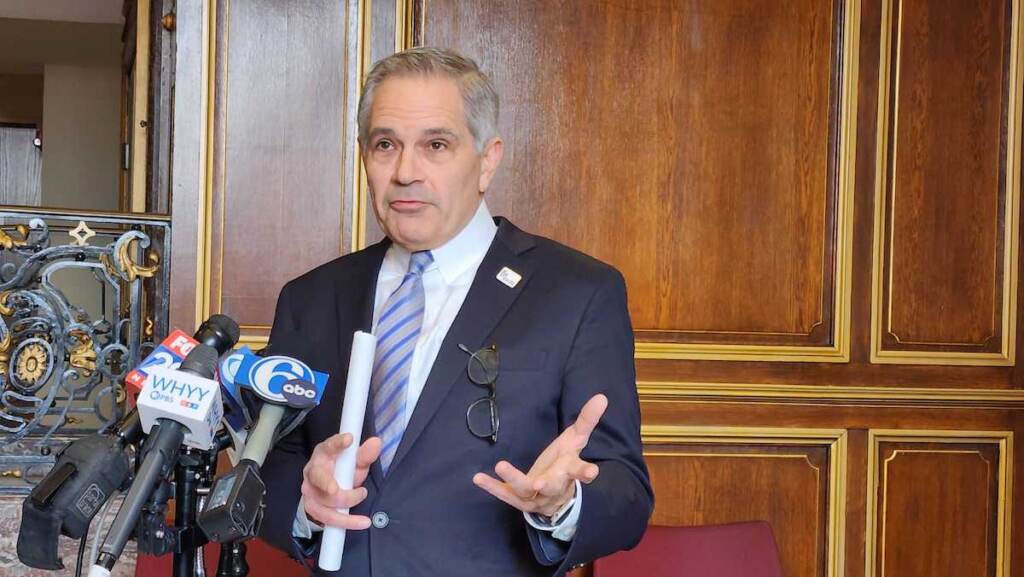 krasner-mistaken-identity-case Krasner speaks at a podium into a number of microphones.