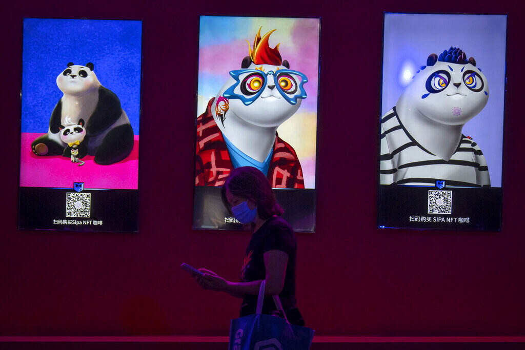A person walks by displayed images of NFTs available for sale.
