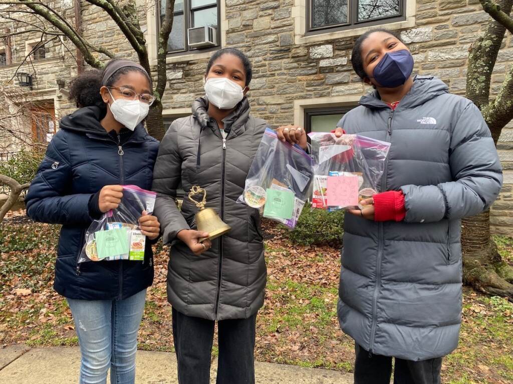 trinity-swarthmore-mlk-day-4 Three people hold up bags and pose for a photo.
