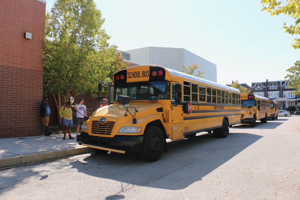 A view of a school bus is outside of a school building.