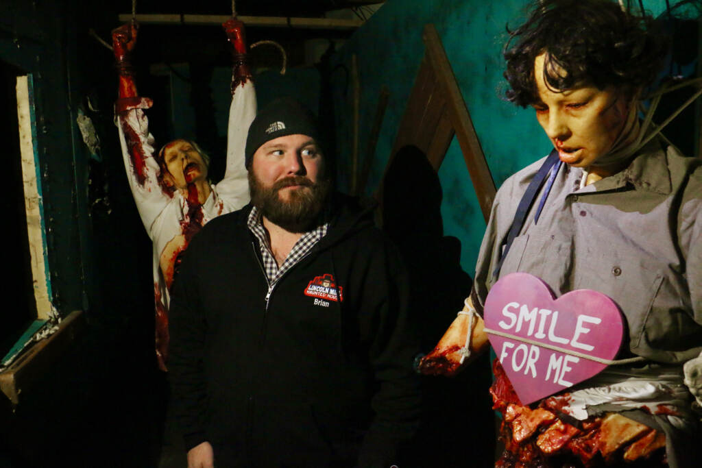 2023 02 06-e lee-brian corcodilos-philadelphia manayunk lincoln mill-valentine haunted house smile for me Corcodilos looks towards a mannequin that looks frightening with a sign on their front shirt which is a pink heart that says