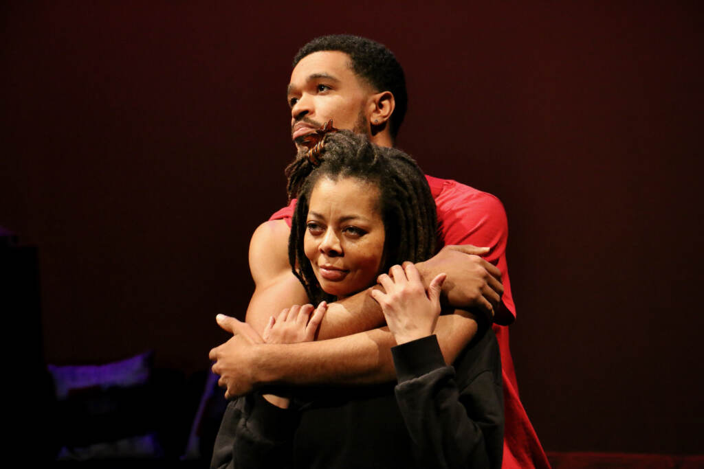 2023 02 14-e lee-alton ray kenya wilson-philadelphia annenberg theater-mecca is burning A man embraces a woman from behind as they gaze into the distance.