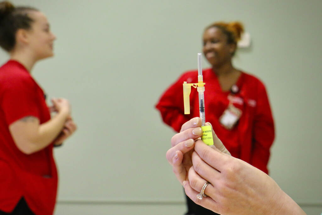 A Camden County health department employee prepares a COVID-19 booster shot while students from the Rutgers-Camden School of Nursing wait to administer vaccines during a clinic in the basement of the United Methodist Church in Haddon Heights.