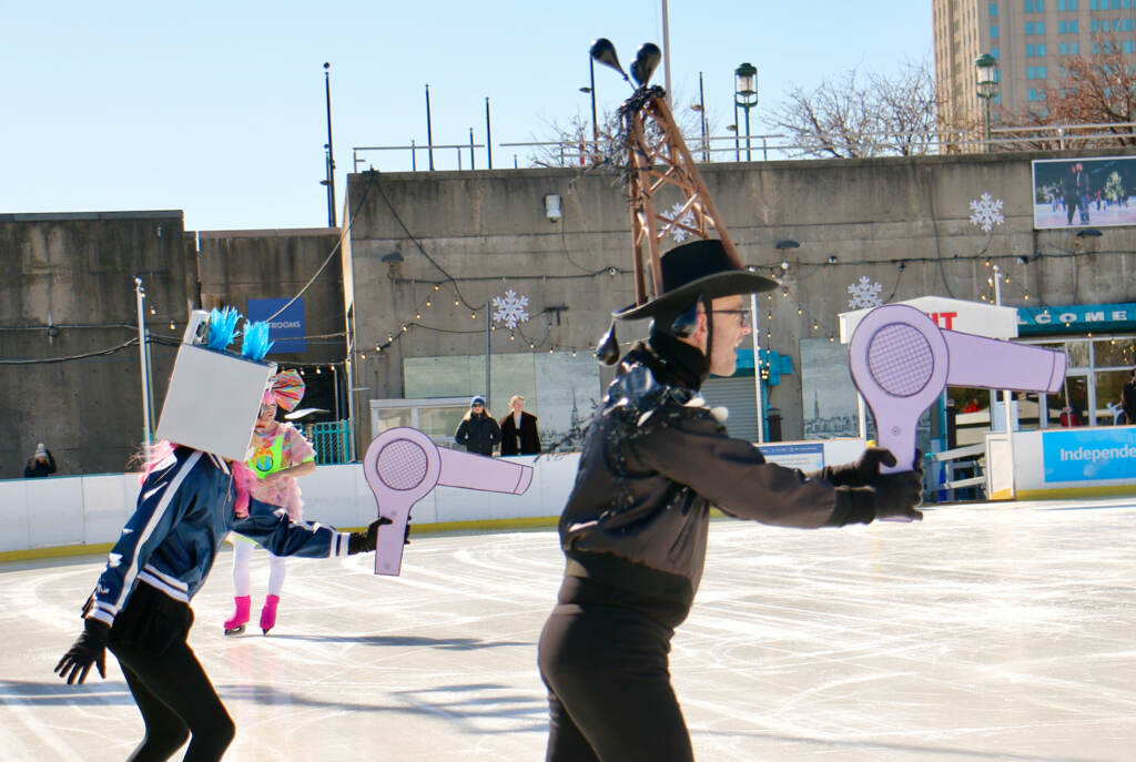 Two performers hold cardboard hairdryers.