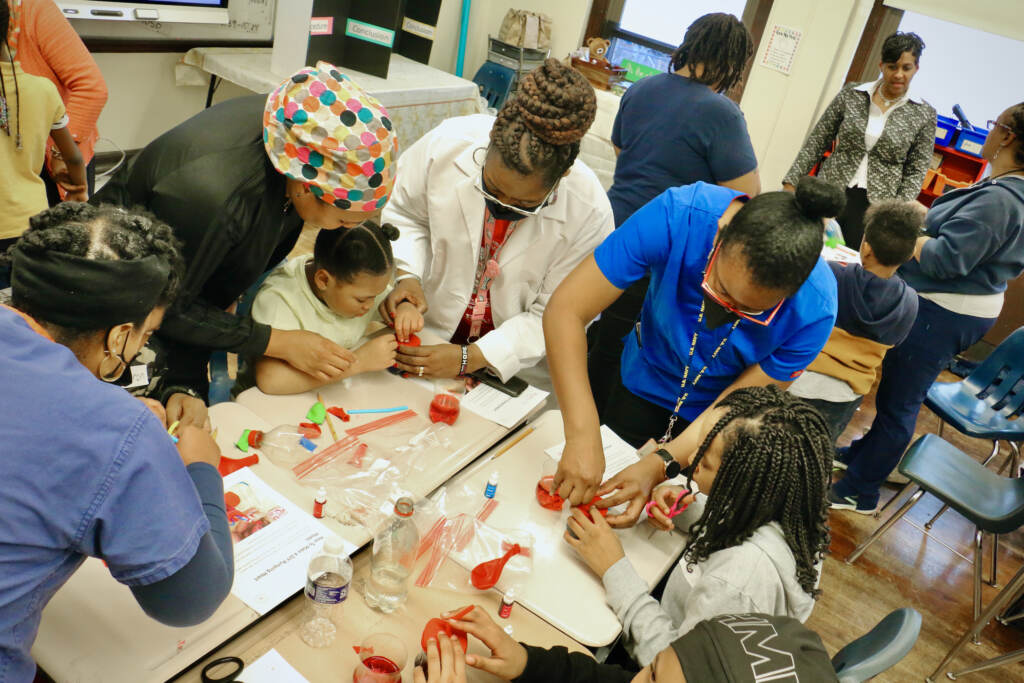 An overhead view of nurses working with students to construct heart models.
