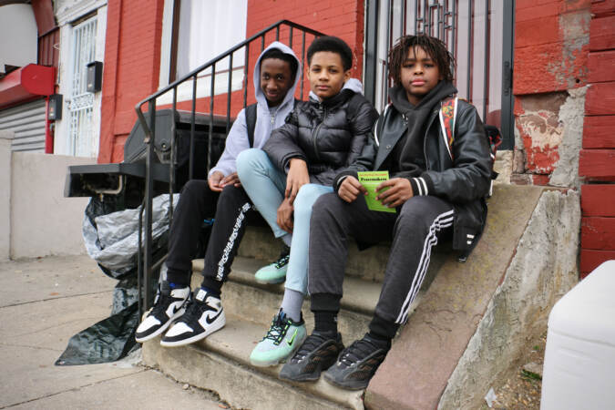 Seventh graders (from left) Corey, Tyree and Mason, stopped to watch the anti-violence march on West Susquehanna Avenue. They said they don't believe the march will make much difference, and talked about how easy it is to get a gun. (Emma Lee/WHYY)