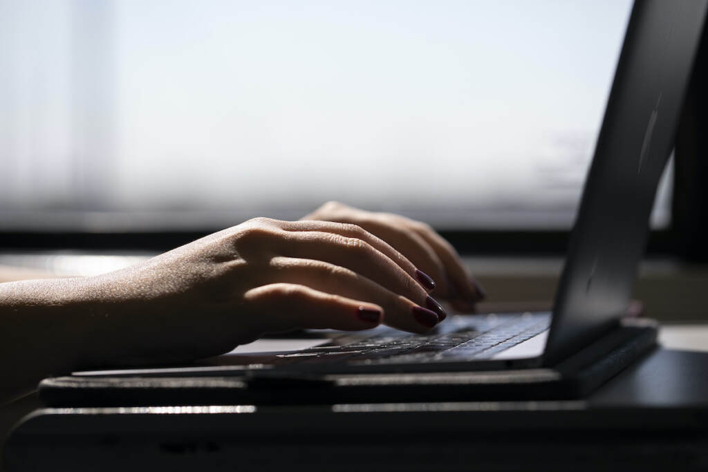 Britain Shorter Workweek A woman types on a laptop while on a train in New Jersey