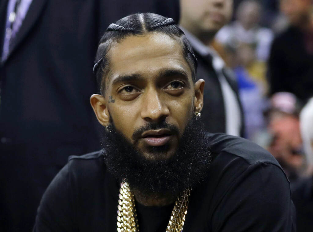 Rapper Nipsey Hussle attends an NBA basketball game between the Golden State Warriors and the Milwaukee Bucks in Oakland, Calif.