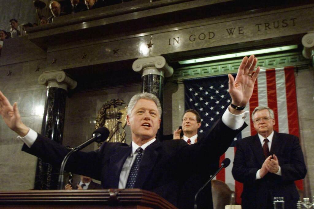 US President Bill Clinton accepts the applause of President Clinton gives a speech from a podium.