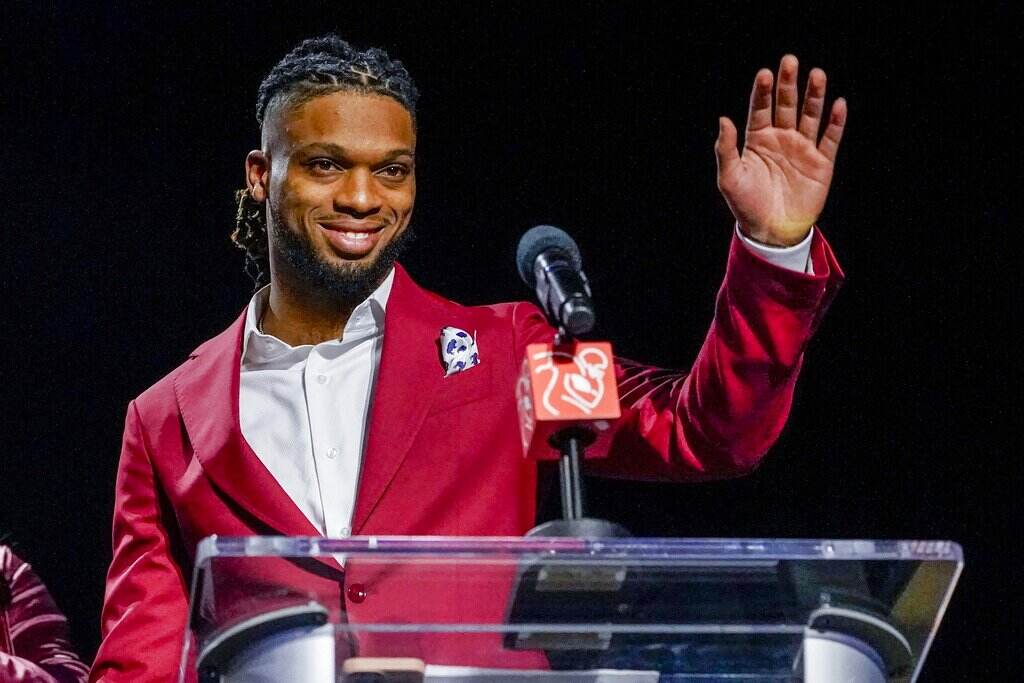 Super Bowl Football Damar Hamlin waves at a podium.
