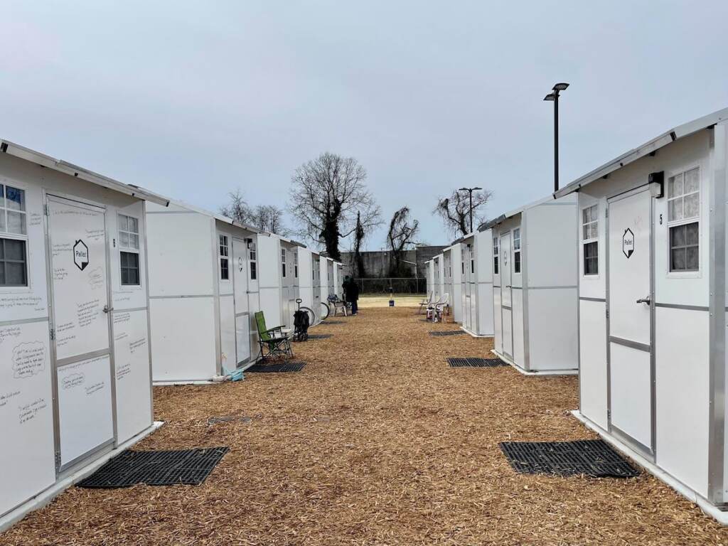 delaware-pallet-village-2 A walkway stretches into the distance, lined by rows of small white homes on either side.