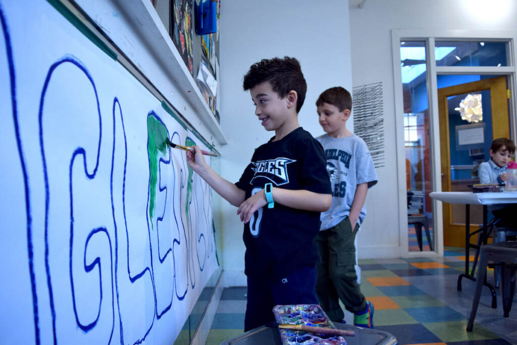 eagles-community-3 A kid paints a letter in a large sign that reads,