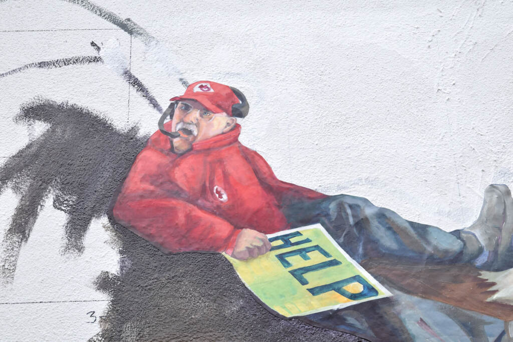 Coach Andy Reid is carrying a sign that reads "help" on a new mural.