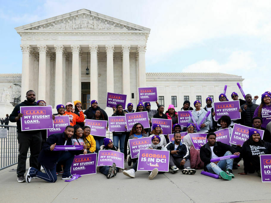 Student loan borrowers and advocates gather Tuesday for a rally during the Supreme Court’s arguments on President Biden’s student debt relief plan. A group of people hold signs in front of the U.S. Supreme Court.