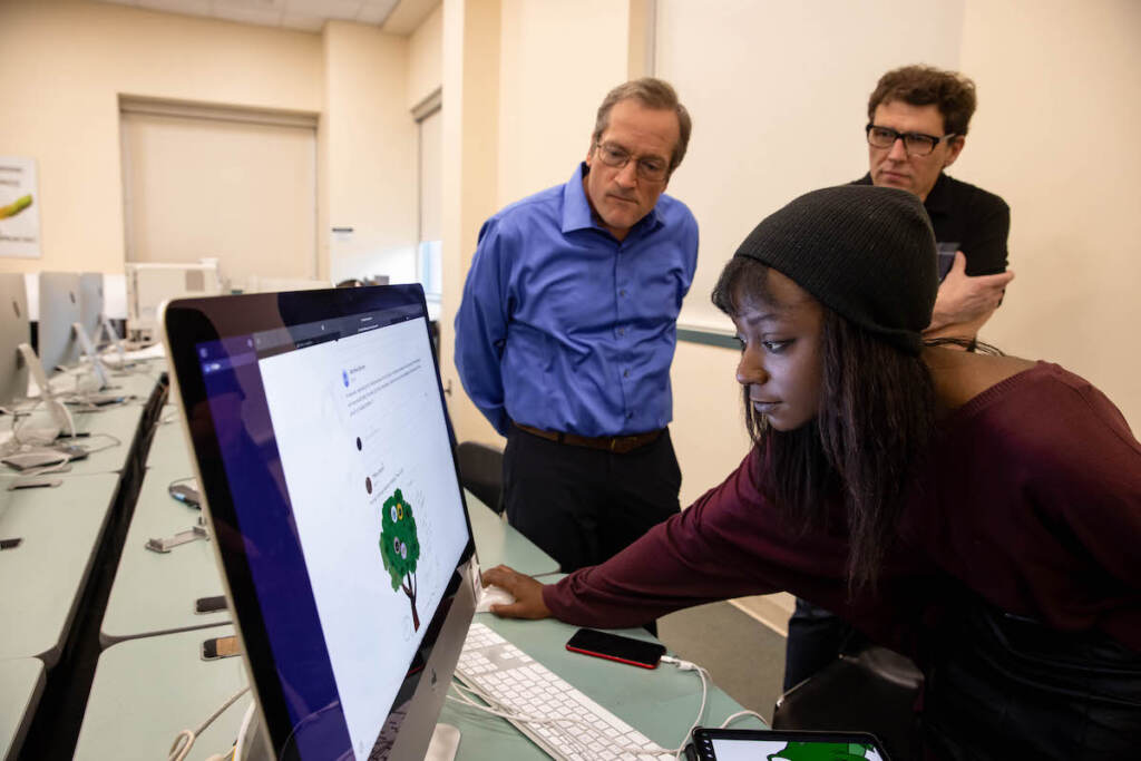 stockton-professor-evolution-album-2 A student looks at a screen as two professors look on behind her.