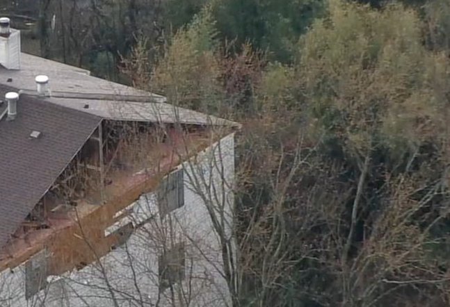Aerial view of a damaged building and trees.