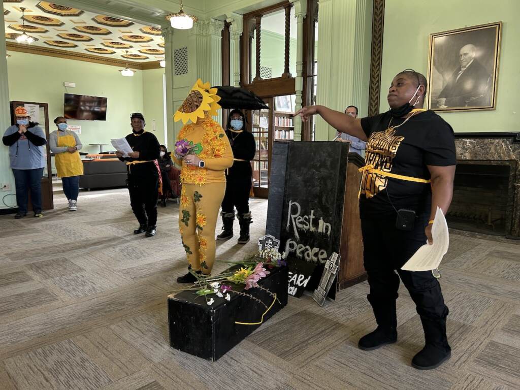 A group performs a skit at the front of a room.