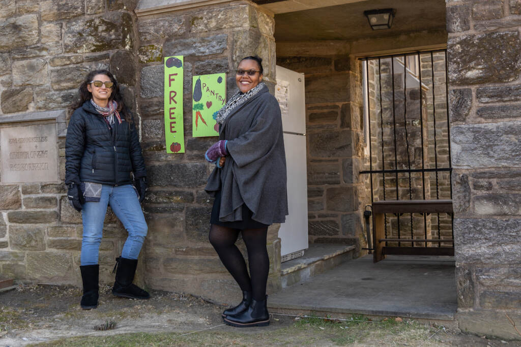 Courtney Heinerici and Nicole Williams pose for a photo, standing next to the doorway of a stone building.