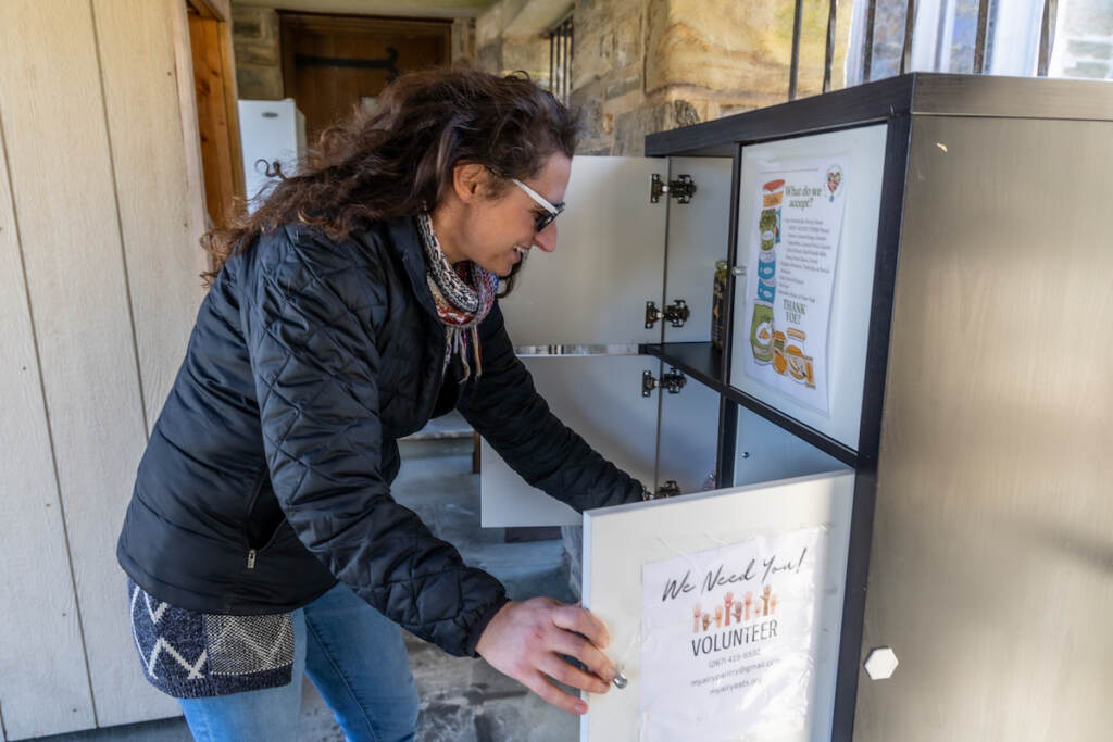 Courtney Heinerici opens the cabinet door of the community pantry.