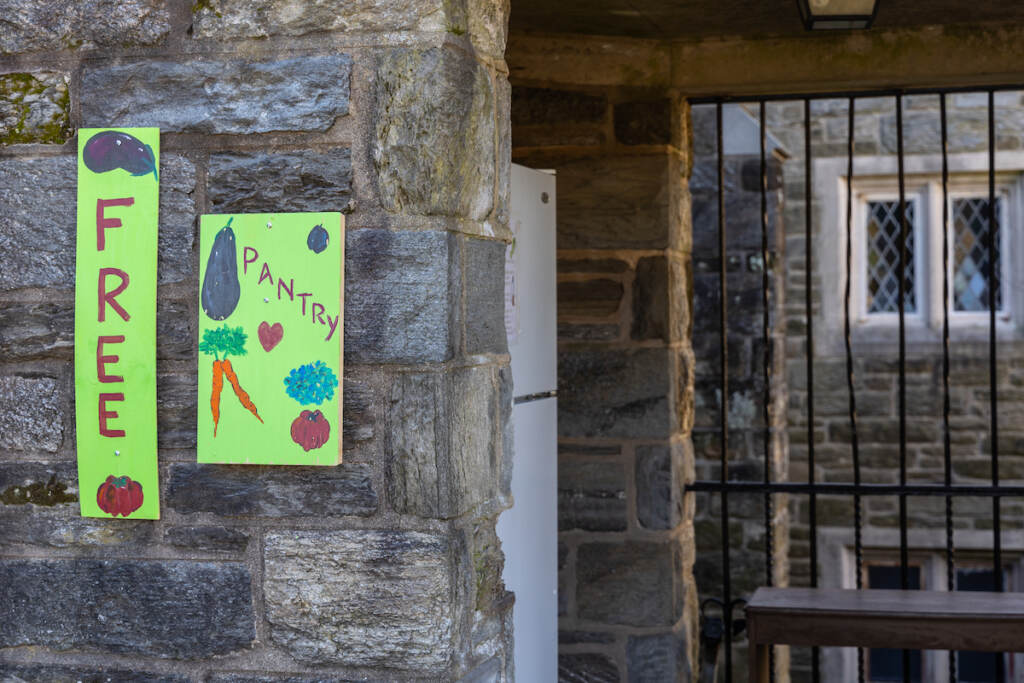 A bright green sign hung on a stone wall displays the words "Free Pantry."