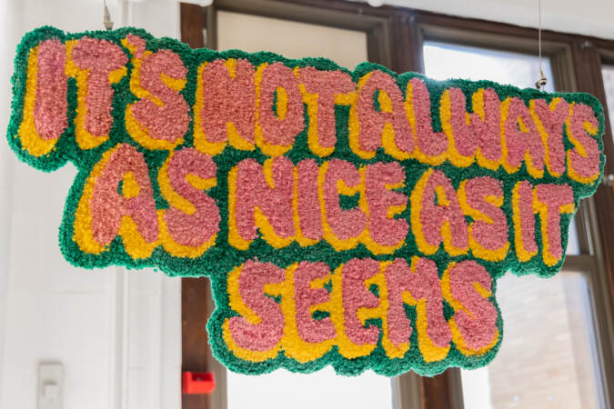 A tufted sign in bright colors reads 