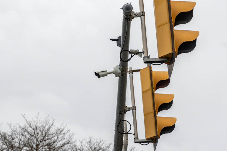 A security camera attached to the same pole as traffic lights is visible.