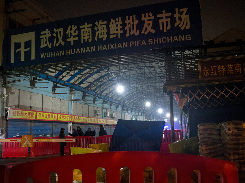 CHINA-HEALTH-VIRUS Security guards stand in front of the Huanan Seafood Wholesale Market in Wuhan, China, on Jan. 11, 2020, after the market had been closed following an outbreak of COVID-19 there. Two studies document samples of SARS-CoV-2 from stalls where live animals were sold. (Noel Celis/AFP via Getty Images)