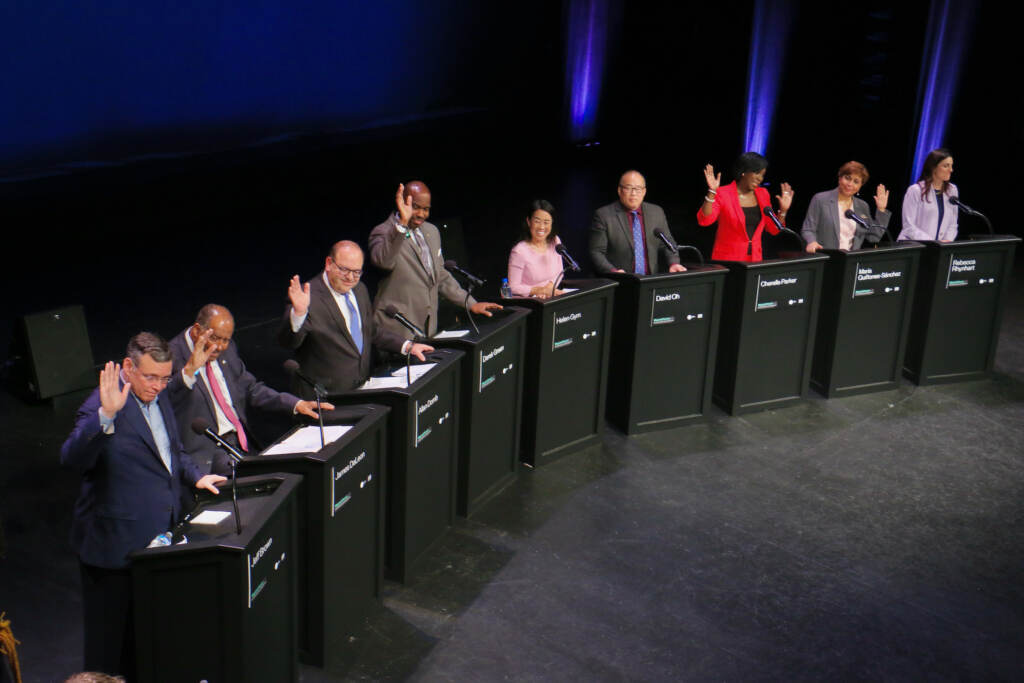 Candidates for mayor of Philadelphia raise their hands when asked who has a TikTok account. The question came during a forum on the performing arts and cultural economy at the Kimmel Center. The candidates are (from left) Jeff Brown, Jimmy DeLeon, Allan Domb, Derek Green, Helen Gym, David Oh, Cherelle Parker, Maria Quiñones Sánchez, and Rebecca Rhynhart. (Emma Lee/WHYY)