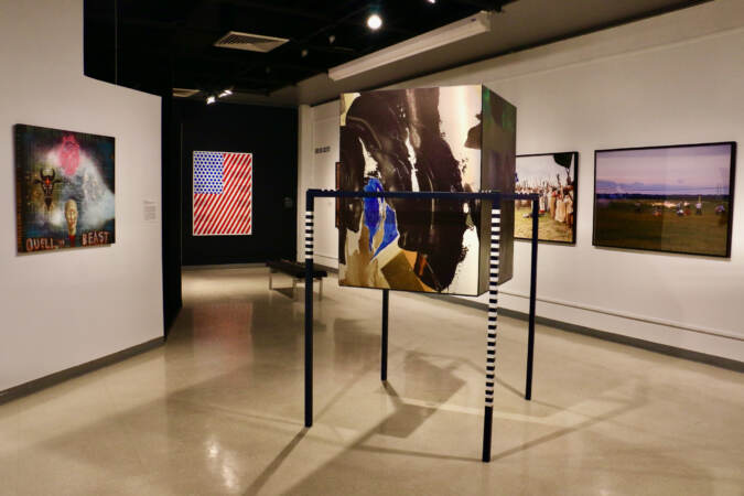 Artwork is hung on the walls and displayed in the middle of a gallery space.