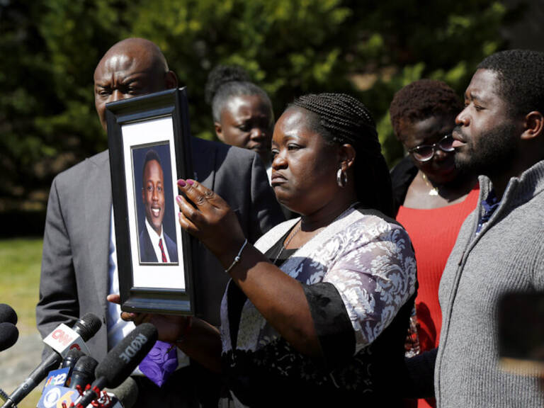 Caroline Ouko, mother of Irvo Otieno, holds a portrait of her son with attorney Ben Crump, left, and her older son, Leon Ochieng at the Dinwiddie Courthouse in Dinwiddie, Va., on Thursday, March 16, 2023. She said Otieno, who died in a state mental hospital March 6, was “brilliant and creative and bright.”  (Daniel Sangjib Min/Richmond Times-Dispatch via AP)