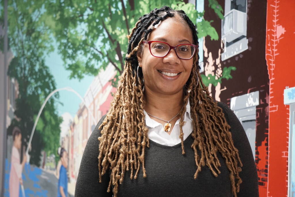 Gooden2 Maxayn Gooden smiles, posing for a photo in front of a mural.